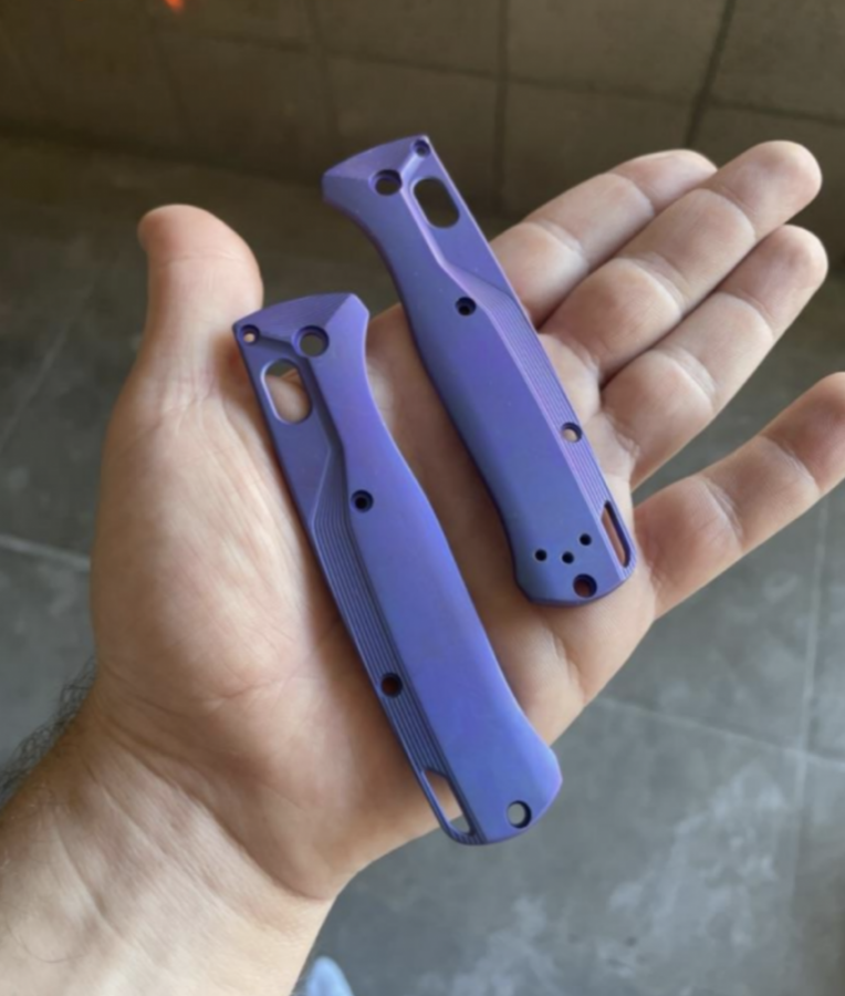 A hand holding two purple tool handles that are made of anodized titanium.