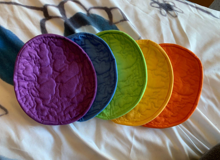 Five differently-colored potholders that are quilted to depict a brain.